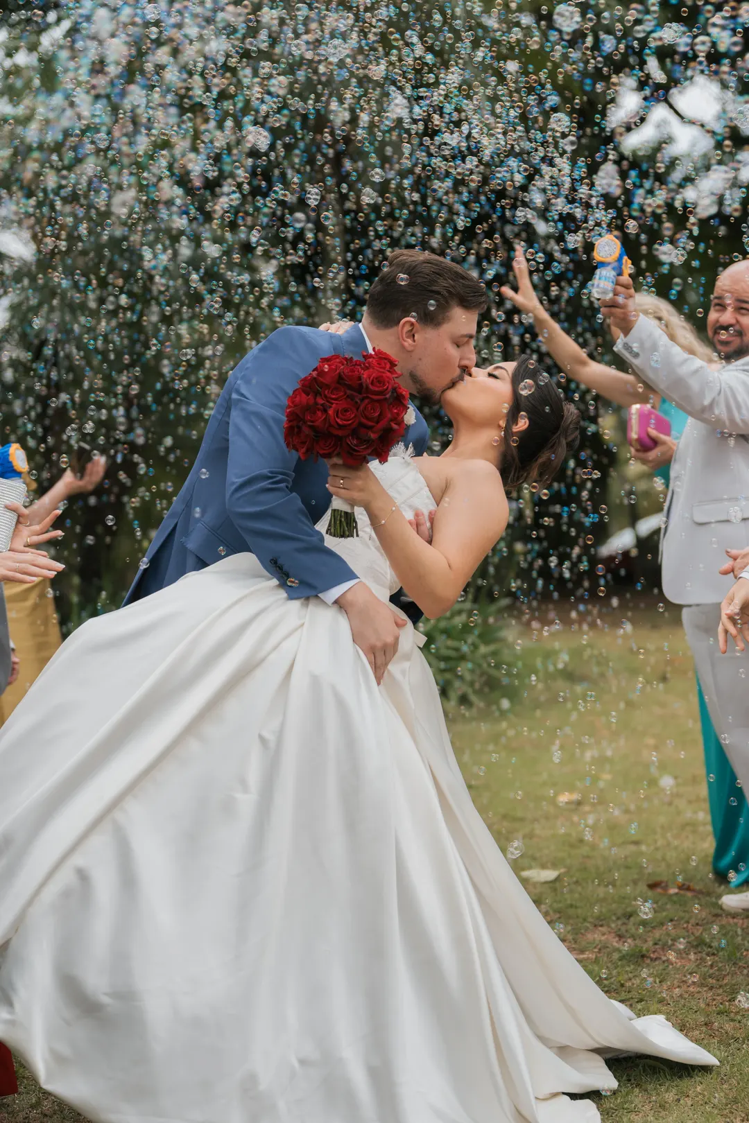 Noivo beijando a noiva na saída, sob chuva de bolhas