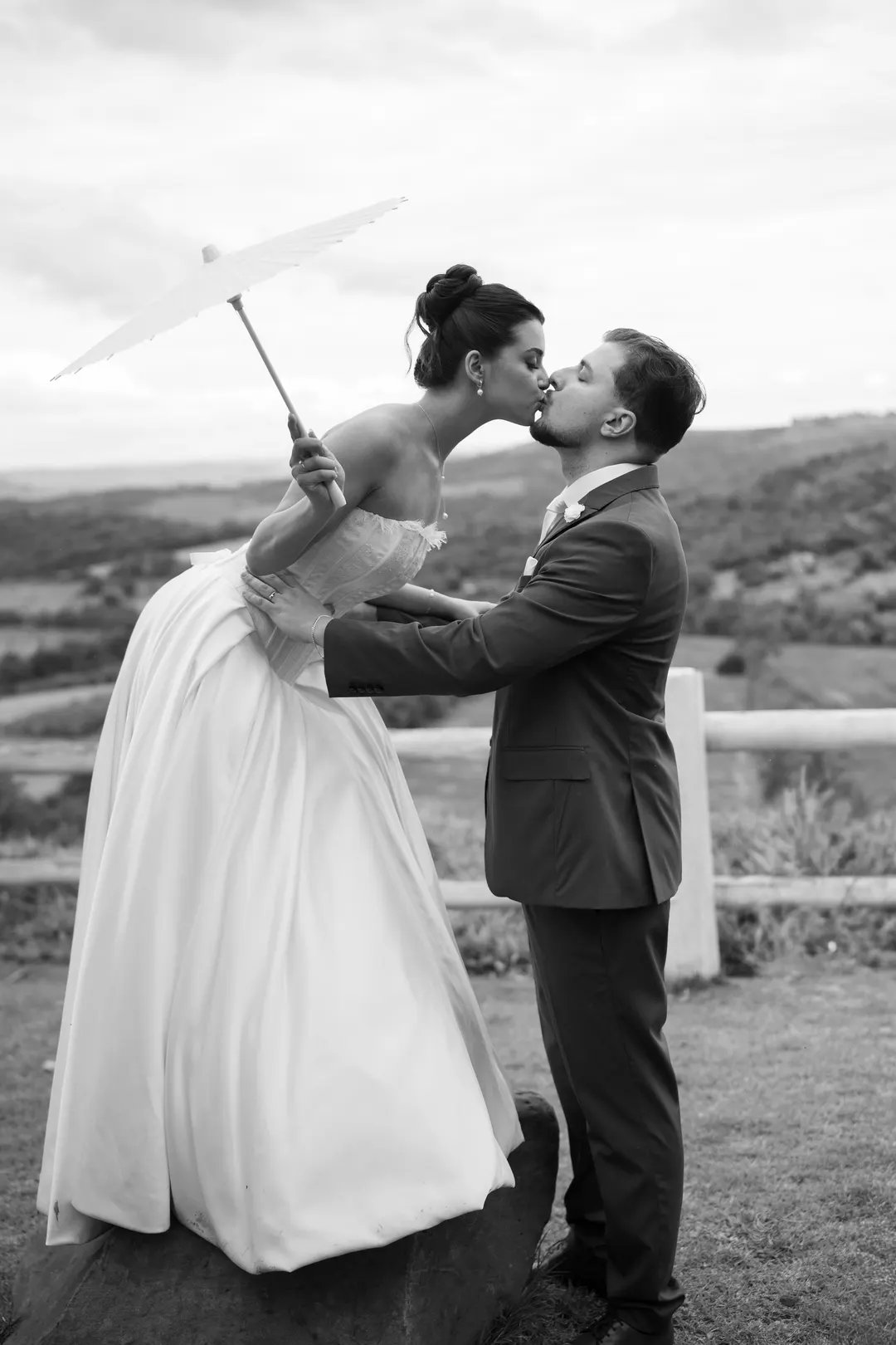 Casal se beijando com a sombrinha erguida, em preto e branco