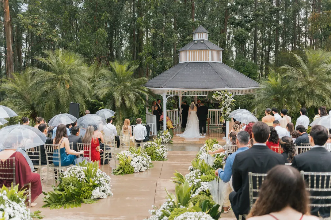 Cerimônia no coreto em meio ao bosque, com convidados de guarda-chuva