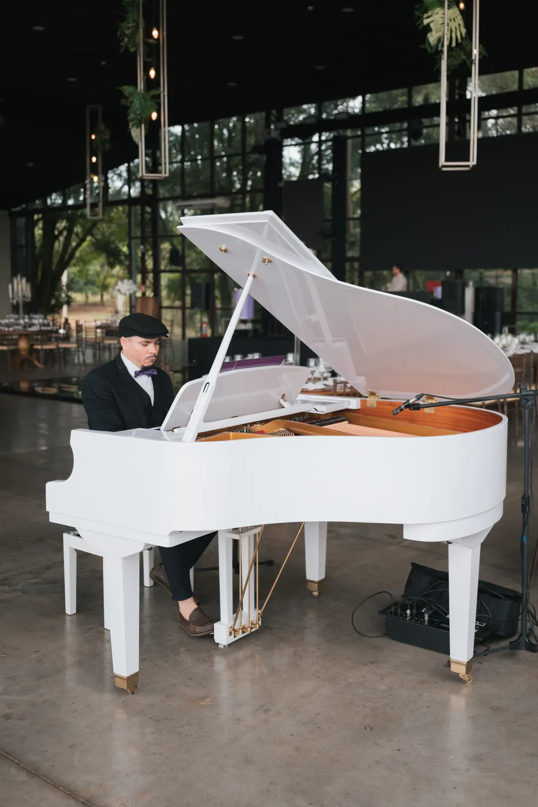 Pianista tocando um piano de cauda branco no salão