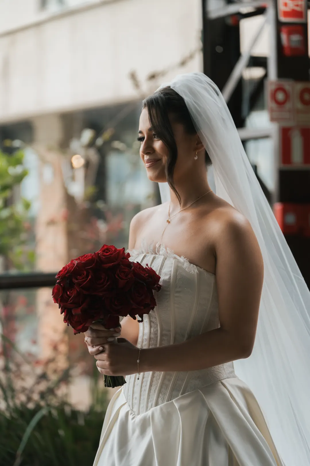 Noiva de vestido tomara que caia com buquê de rosas vermelhas