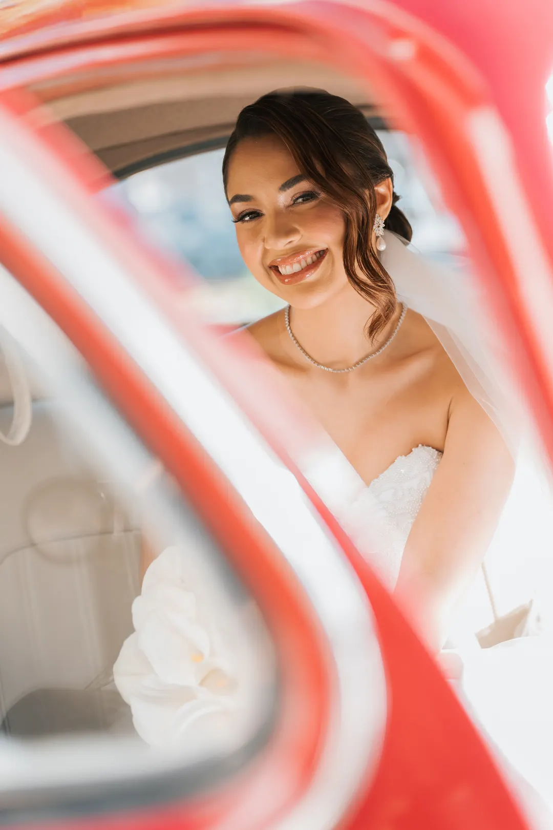 Noiva sorrindo dentro de um carro antigo vermelho