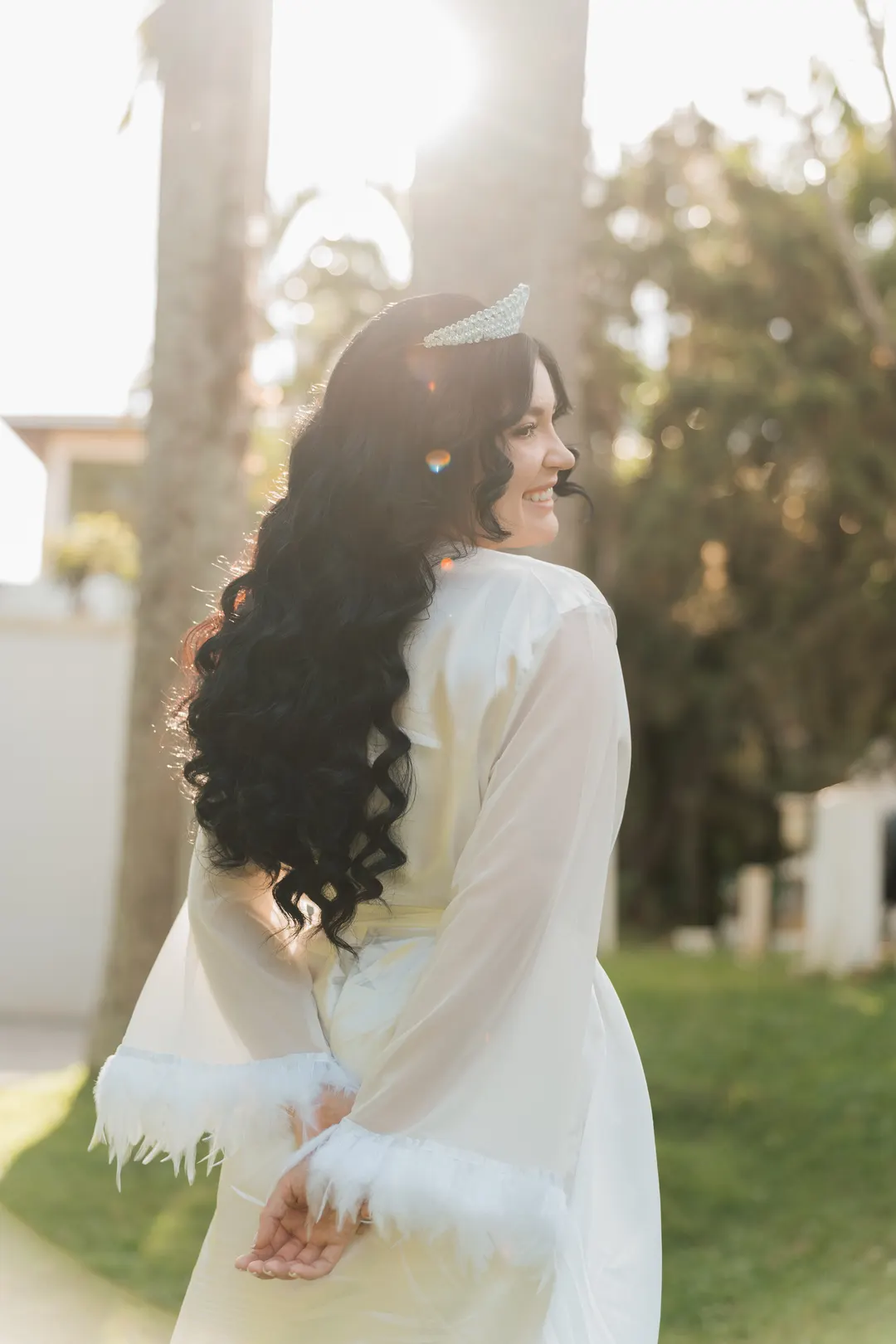 Noiva de roupão branco de costas, olhando para trás no jardim