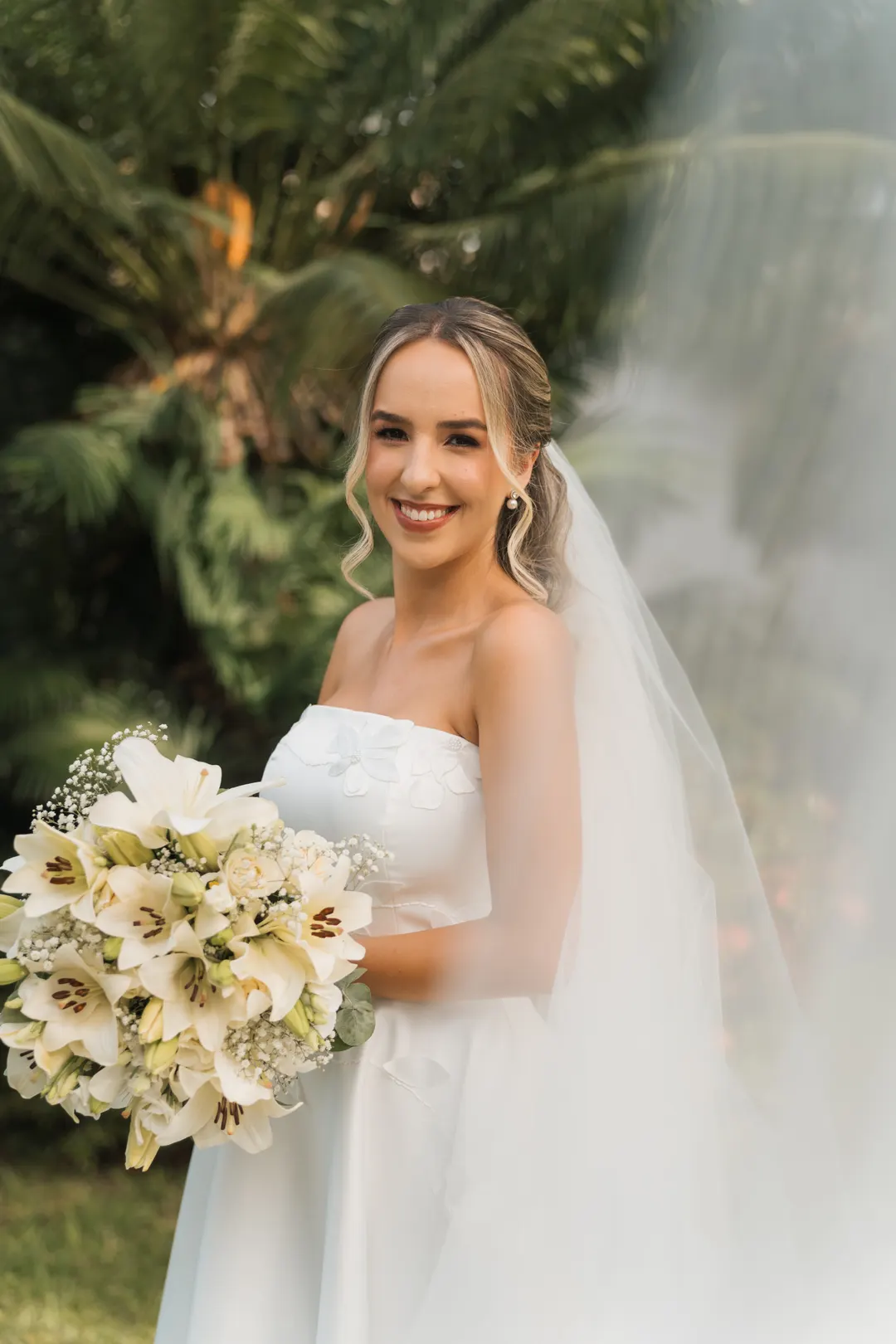 Noiva sorrindo com o buquê no jardim
